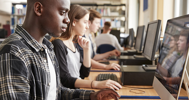 Group Of Students Using Computers In College Library